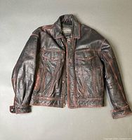 Front view of black leather jacket with red stitching showing pockets and zipper