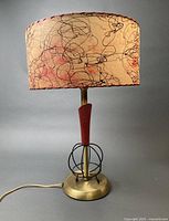 Full view of lamp lit showing shade design, red fin, wire cage and base