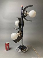 Full view of chrome and black three-head table lamp with reference Coca-Cola can for scale