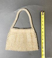 Front view of beaded handbag alongside measuring tape
