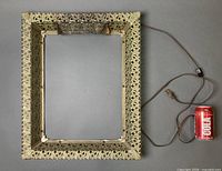 Front view of ornate metal frame with cord and soda can for scale