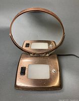 Round swiveling mirror on illuminated base with power cord