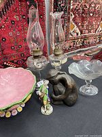 group shot showing all items: majolica bowl, two oil lamps, porcelain figurine, metal monkey, glass compote