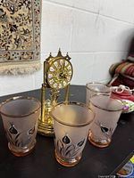 Four frosted tumblers, brass-tone clock behind