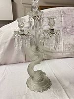 full view of candelabra showing three arms, prisms, and dolphin base