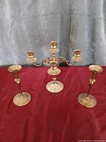 front view of brass five-arm candelabra and two single candlesticks
