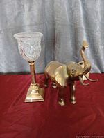 Brass elephant figurine beside brass-base table lamp with clear glass shade