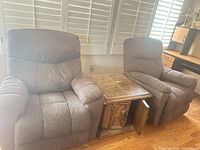 Pair of brown fabric recliners with wooden console table between