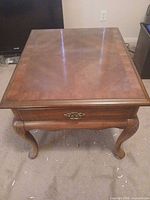Top view of brown veneer Queen Anne end table showing parquet pattern top, drawer front and cabriole legs