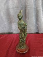 Full view of carved jade figure on wooden stand