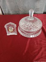 Crystal dish with lid and small crystal clock displayed on red surface