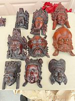Front view of eleven carved masks displaying styles and finishes