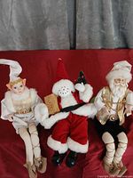 Front view of three Christmas dolls on red surface
