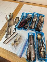 Assorted flatware sorted in blue baskets showing range of pieces