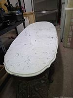 Full view of oval marble coffee table on carved wooden base