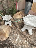 Both concrete lanterns next to rocks outdoors