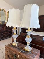 Pair of crystal and brass lamps with shades on chest