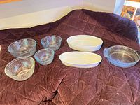Group view of four ribbed glass bowls, two white oval dishes, one round fluted dish