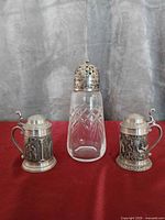 Group shot of two mini steins and sugar shaker on red surface