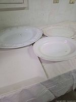 Four platters shown on table; three belong to lot (two oval, one square) showing overall condition