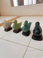 All four stone duck figurines lined up on tile surface