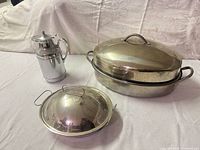 overview of all three stainless items: coffee/tea carafe, large oval roaster with lid, small round roaster with lid