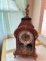 Full view of clock showing case, dial, ormolu mounts and finial