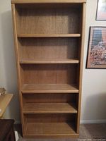 Front view of full-height light oak veneer bookcase showing five adjustable shelves and overall condition
