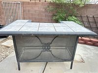 Front view of patio bar showing tile top and mesh metal front panel