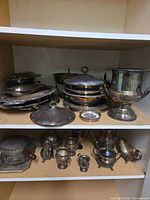 Overall view of stacked trays, covered bowls, urn and tea service on shelving