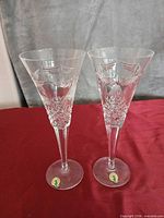 Pair of Waterford cut crystal champagne flutes standing upright on red cloth