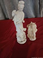 Tall Guanyin figure and smaller male figure side by side on red cloth