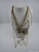Multiple necklaces draped on display bust showing overall quantity and variety