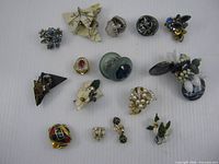 Overview of all fifteen pairs assorted clip-on earrings laid out on white background