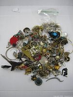 Full pile of assorted single earrings and small bag of backs