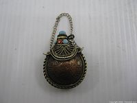Front view of Tibetan snuff bottle pendant showing copper body, brass filigree top and stones