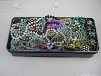 Top view of closed tin densely filled with assorted jewelry pieces
