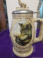 Front angled view showing printed wolf image, relief design, and pewter lid with wolf finial