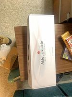 Sealed white Aklot Ukulele retail box on table