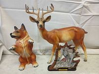 Front view of three wildlife figurines: ceramic fox, ceramic deer, resin wolf scene