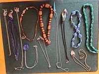 Overall lot showing all thirteen necklaces laid out on board