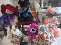 Group shot showing all eight plush toys and cloth dolls with clothing and accessories visible