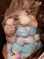 bag filled with assorted skeins of yarn in various colors and weights, labels visible