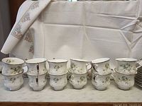 Eight floral bone china teacups with silver rims stacked in groups of two
