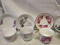 Front view of three teacups and four saucers showing patterns and 25th Anniversary design