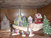 Full view of Christmas village set showing buildings, trees, figurines and lamp