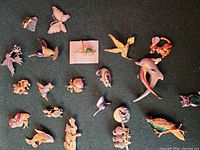 All brooches laid out on dark background showing variety of animal and insect motifs, metal finishes and enamel colours