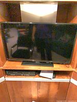 Front view of TV on shelf with stand and player below