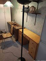 Overall view of lamp, desk, cabinet, chair, shelves