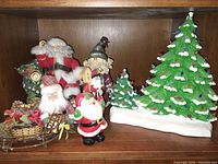 Full view of lot showing four Santa figures, ceramic tree, sleigh decor